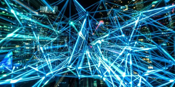 Web of glowing blue lines and nodes overlaid on a blurred city skyline at night