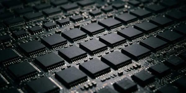 A close-up of a densely packed circuit board with numerous black microchips, set against a dark background.