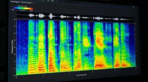 The image displays a spectrographic audio analysis software window showing a complex sound wave pattern in vibrant green and blue hues.