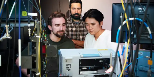 Portrait of the three researchers surrounded by instrumentation