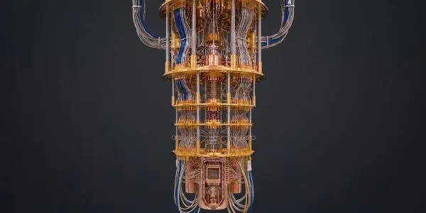 A gold cryostat hanging against dark grey, the chip mount visible at its base