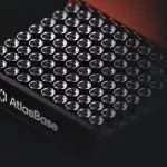 The close-up shot displays a sleek, black device with numerous circular openings, set against a dark background.