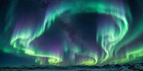 Green aurora curtains over a frozen coast