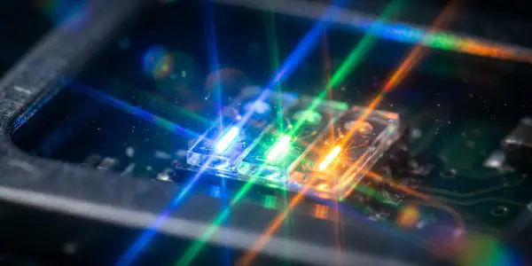 Three tiny blue, green and orange light emitters on a chip with crossing colour streaks