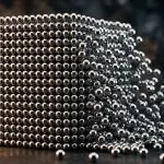 A cube of chrome spheres collapsing into a scatter