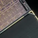 A microchip die, intricately patterned in gold and silver, is dramatically lit against a black background, suggesting advanced technology.