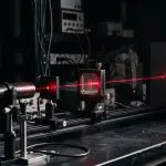 Red laser passing through a slit on an optical rail and making an interference pattern on a screen