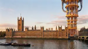 The Houses of Parliament sits alongside a giant golden teapot structure on the River Thames at sunset.
