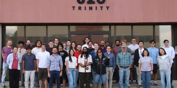 A group poses outside a building marked “820 Trinity.”