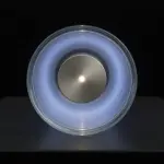 A circular device glows with blue light on a dark surface, suggesting advanced technology and precision engineering.