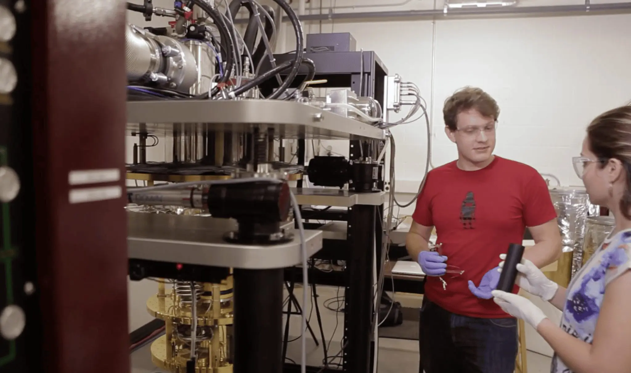 Two scientists are examining a complex piece of scientific equipment in a laboratory setting.