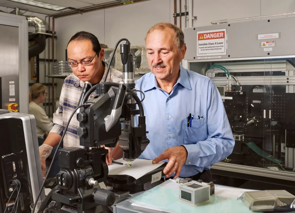 Hsianghan Hsu (left) and John Knickerbocker (right) inspect a polymer optical waveguide module under a microscope at IBM Research's global headquarters in Yorktown Heights, New York.