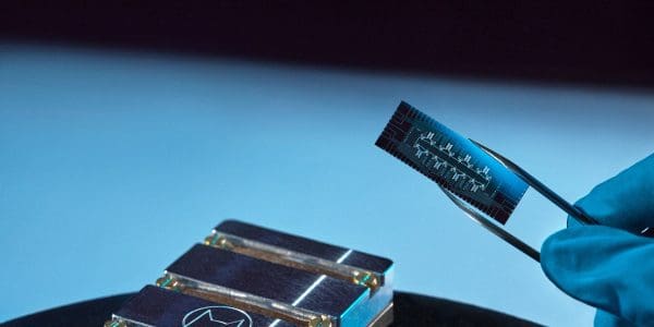 Alice and Bob Helium cat-qubit chip held in tweezers above its sample mounts