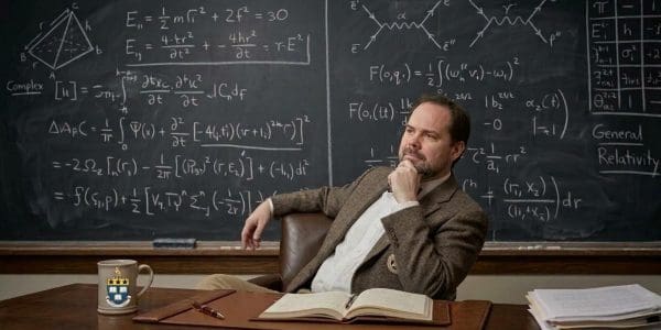 Illustration of Ben Varcoe, Leeds quantum physicist, seated at a desk in front of a chalkboard