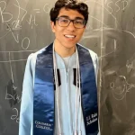 Luca Nashabeh wearing Columbia University regalia in front of a blackboard with physics equations before his Columbia