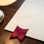 An embossed official document with a blind seal under a desk lamp